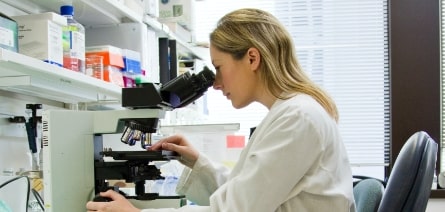 Femme en train de regarder dans un microscope dans un laboratoire de recherche en innovation